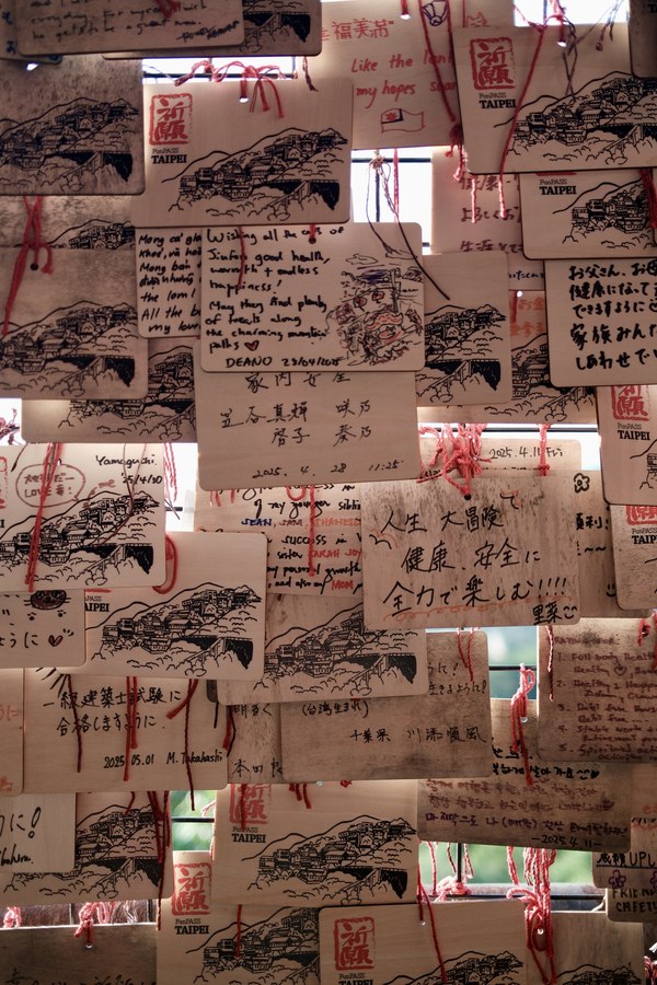 Wooden wish plaques with handwritten messages, tied with red string